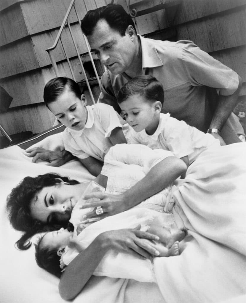 Elizabeth Taylor bottle-feeding newborn Liza Todd with her sons Christopher and Michael H. Wilding, and her husband Michael Todd observing.