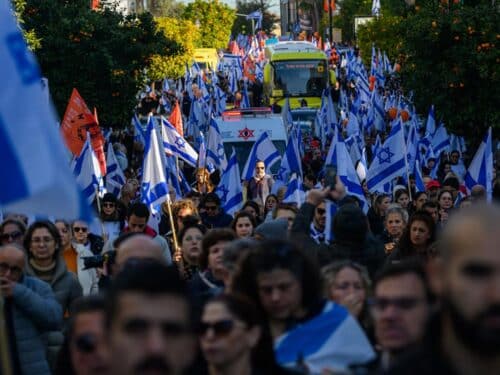 Thousands of people line the street to watch and pay their respects as the funeral procession carrying the caskets of Shiri Bibas, Kfir Bibas and Ariel Bibas pass by with the family in minibuses behind them on its way to the funeral on February 26, 2025 in Rishon LeZion, Israel.