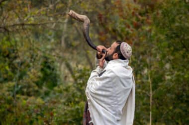 An Ultra-Orthodox Jewish pilgrim blows a shofar on the street near the tomb of Rabbi Nachman while celebrating Rosh Hashanah, the Jewish New Year, amid the ongoing war in Ukraine. This takes place in Uman, Ukraine, on October 3, 2024. (Photo by Maxym Marusenko/NurPhoto via Getty Images)