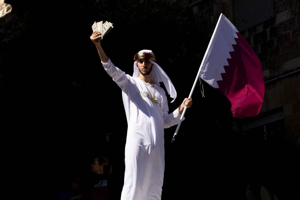 A costumed protester holds a Qatar flag and money during a rally against the Israeli government on March 19, 2025 in Jerusalem.