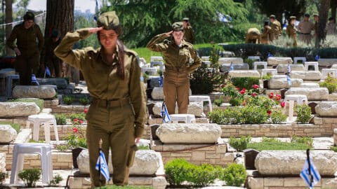 Israeli soldiers salute after placing the national flag on the graves of fellow soldiers at the Mount Herzel military cemetery in Jerusalem on April 28, 2025, ahead of the Memorial Day for fallen soldiers, or Yom HaZikaron in Hebrew. Israel commemorates Memorial Day to pay tribute to soldiers and victims of attacks, just before the celebrations of the anniversary of its creation according to the Jewish calendar. (Photo by Menahem KAHANA / AFP) (Photo by MENAHEM KAHANA/AFP via Getty Images)
