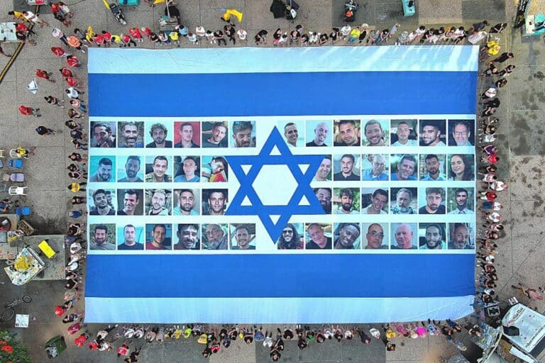 Protesters gather in Hostage Square and hold a giant Israeli flag with photos of hostages on it, demanding the return of the hostages held in Gaza, as protests and strikes continue in Tel Aviv, Israel on August 17, 2025. (Photo by Yair Palti/Anadolu via Getty Images)