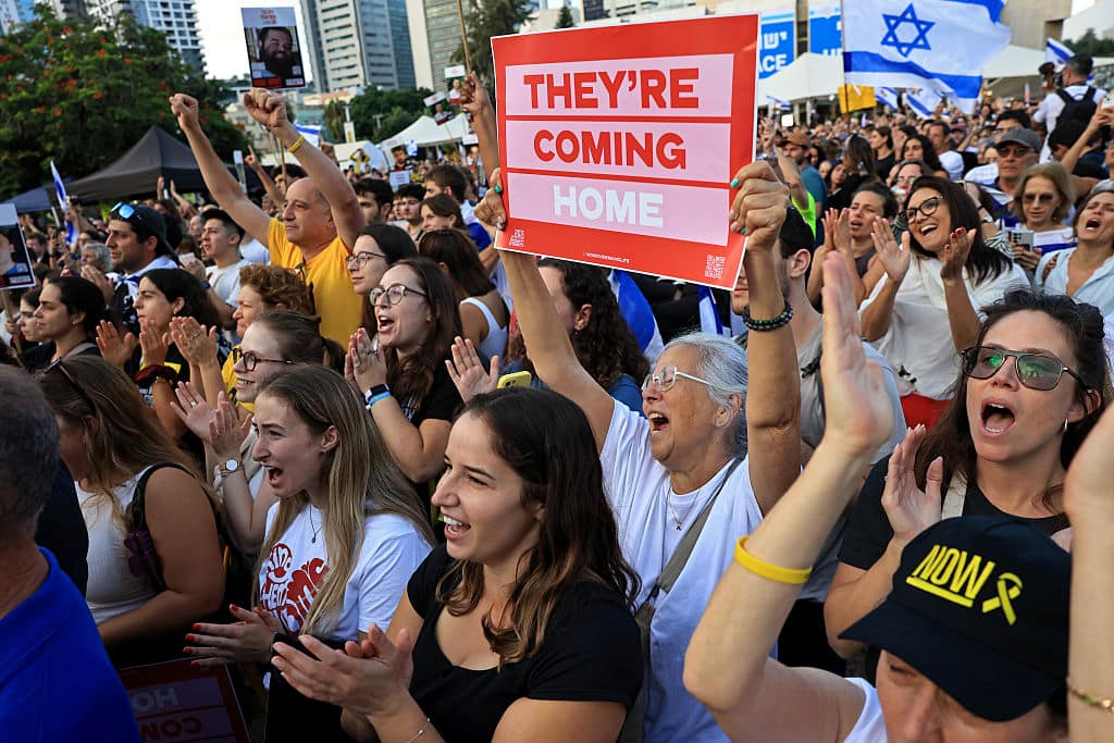 TEL AVIV - OCTOBER 13: People react as they watch the hostage release live stream at Hostages Square on October 13, 2025 in Tel Aviv, Israel. The ceasefire deal between Israel and Hamas has brought an end to the two years of war that followed the attacks of Oct. 7, 2023. A condition of the deal was the immediate return of 48 hostages held in Gaza, around 20 of whom were believed to be alive. (Photo by Chris McGrath/Getty Images)