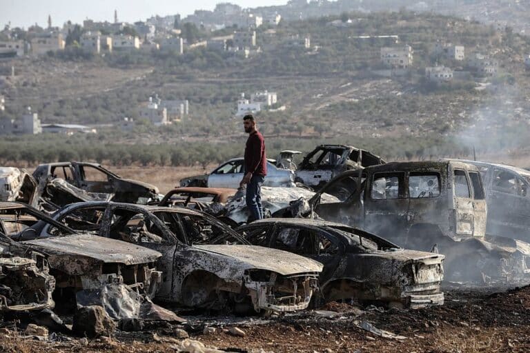 A Palestinian checks a vehicle scrapyard after Israeli settlers burned it in the town of Huwara, south of the West Bank city of Nablus, on Nov. 21, 2025. According to the official WAFA news agency, Israeli settlers set fire to a vehicle scrapyard here on Friday evening. (Photo by Ayman Nobani/Xinhua via Getty Images)