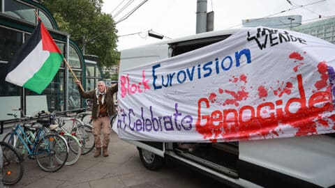 An activist stands next to a banner reading "Block Eurovision" to protest against the participation of Israel ahead the first semifinal of the Eurovision Song Contest, Vienna, Austria, on May 12, 2026. (Photo by Radek MICA / AFP via Getty Images)