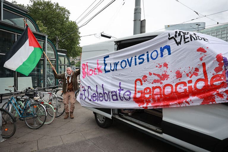 An activist stands next to a banner reading "Block Eurovision" to protest against the participation of Israel ahead the first semifinal of the Eurovision Song Contest, Vienna, Austria, on May 12, 2026. (Photo by Radek MICA / AFP via Getty Images)