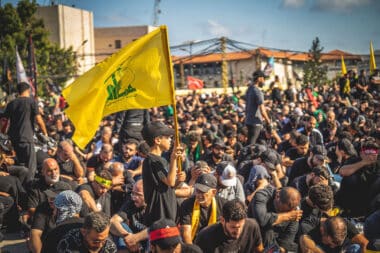 A boy holds a yellow Hezbollah flag while walking among a crowd during a mourning ceremony in the southern suburbs of Beirut, Lebanon, on June 26, 2026. The event, organized by Hezbollah, marks Ashura, a period culminating on the tenth of the Islamic month of Muharram that commemorates the seventh-century killing of Prophet Mohammed's grandson, Imam Husayn. (Photo by Nael Chahine / Middle East Images / AFP via Getty Images)