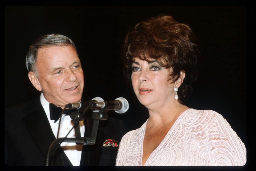 Actress Elizabeth Taylor speaks while entertainer Frank Sinatra watches January, 1982 in Washington, DC. Taylor was awarded for her public support of the Simon Wiesenthal Center, an international Jewish human rights organization dedicated to preserving the memory of the Holocaust by fostering tolerance and understanding. (Photo by Diana Walker/Liaison)