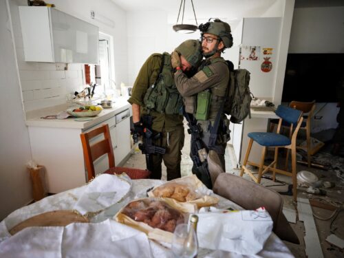 Soldiers weep in the wreckage of a home at Kibbutz Kfar Aza, where leftover wine and challah from a holiday meal are still on the table, four days after the October 7 massacre. Photo by Ziv Koren/Polaris Images