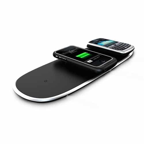 Two smartphones are placed on a sleek, black wireless charging pad. One phone shows a green battery icon indicating its charging. The pad and phones are on a white background.